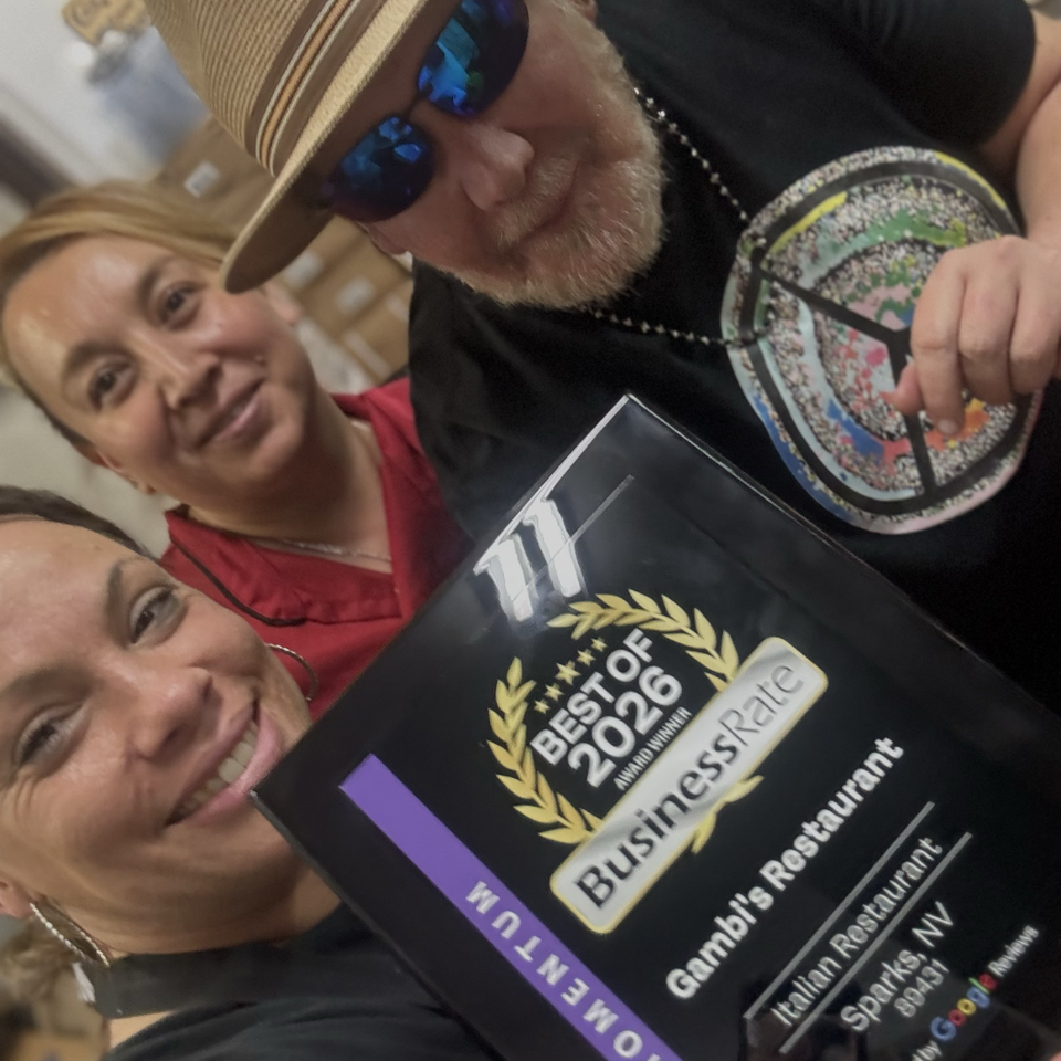 Three smiling people pose closely for a selfie, with one wearing sunglasses and holding a Business Recognition award plaque.